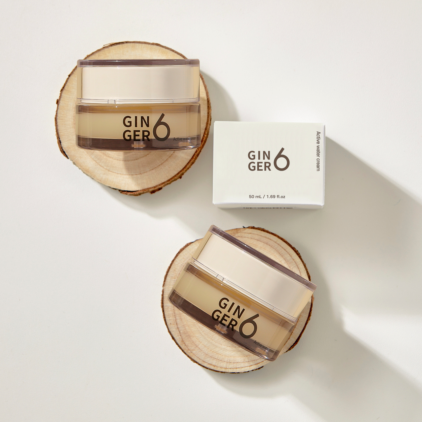 Top-down view of Ginger6 Active Water Day Cream jars and packaging box resting on natural wood slices