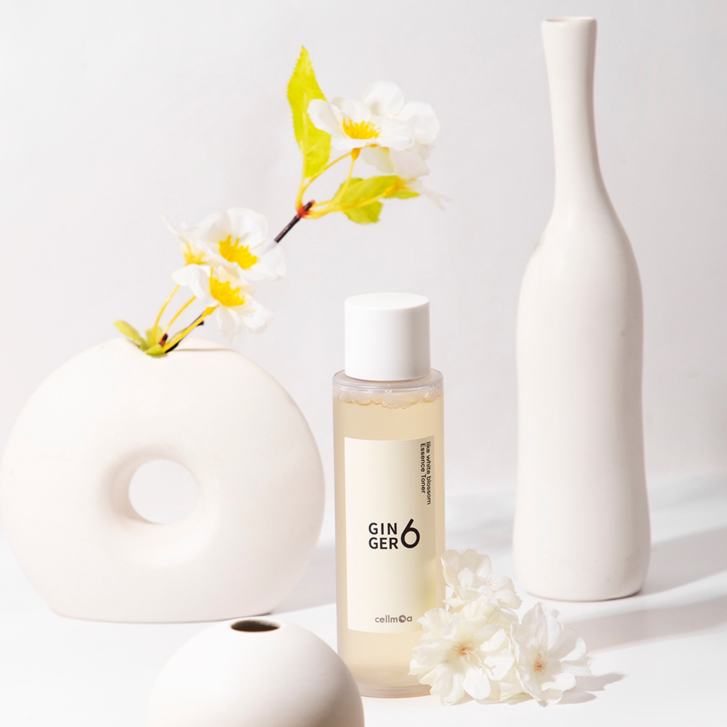 Ginger6 Essence Toner displayed with modern white ceramic vases and a delicate flower