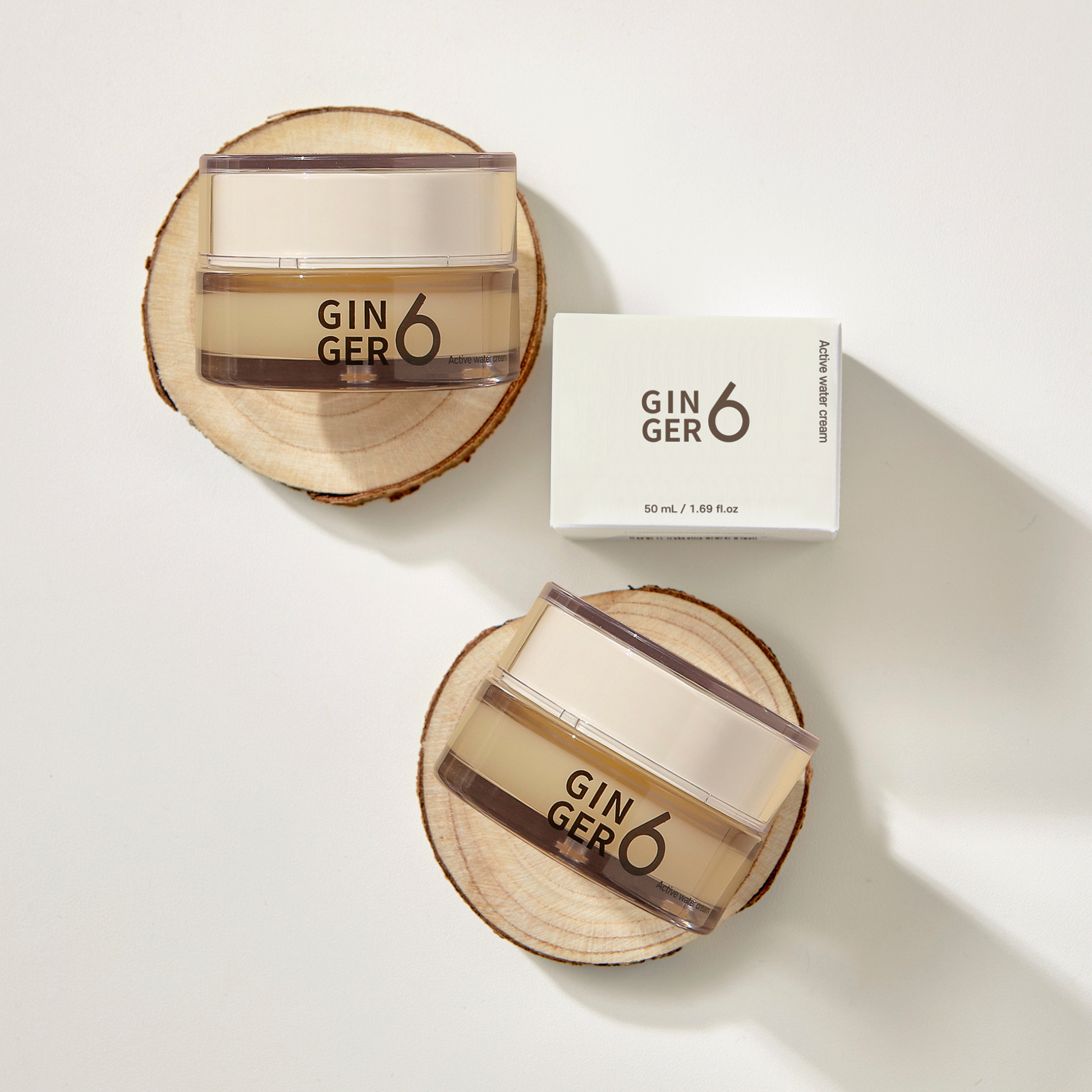 Top-down view of Ginger6 Active Water Day Cream jars and packaging box resting on natural wood slices