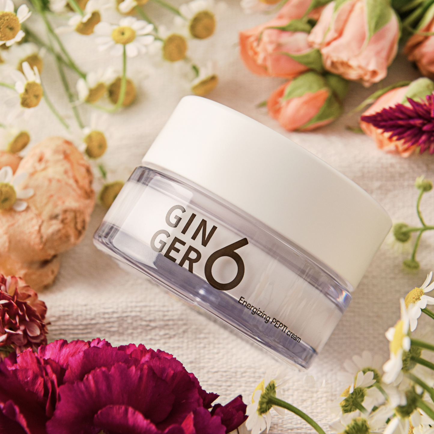 Ginger6 Energizing PEPTI Night Cream surrounded by fresh pink and purple flowers on a textured cloth