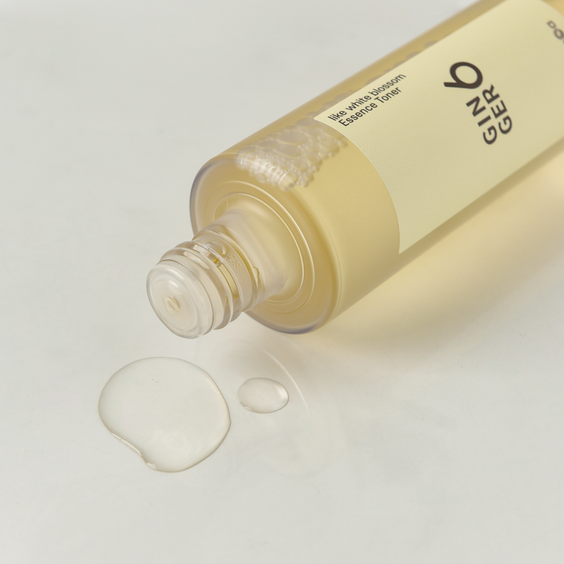 Close-up of Ginger6 Essence Toner bottle dispensing a clear, hydrating liquid drop on a white surface