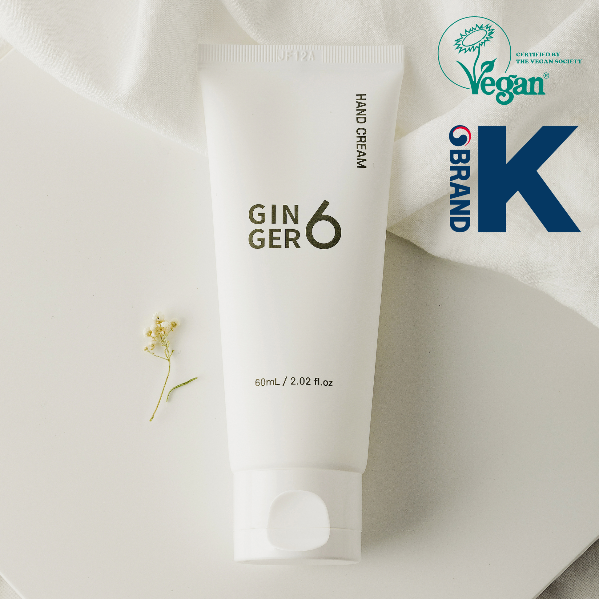 Ginger6 Hand Cream 60ml tube with a delicate white flower, featuring Vegan Society and Brand K logos