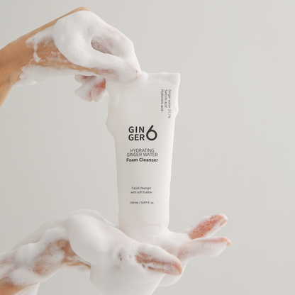 Hands holding Ginger6 hydrating ginger water foam cleanser, demonstrating its rich and soft micro-bubble lather